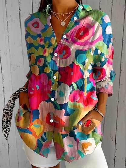 Model wearing the shirt in a bold abstract print of pink, red, blue and green blocks, with sleeves rolled up. 5