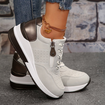 Light grey trainers seen from the side, showing the zip, perforations and metallic heel panel 3