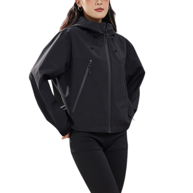 Close-up of the black jacket zipped up with one hand in a pocket, showing the hood drawcords and slanted chest zips. 17