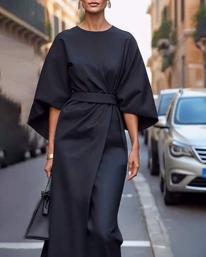 Black wrap-front dress with sleeves flaring at the elbow, worn with drop earrings and a small handbag 6