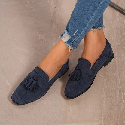 Navy tasselled loafers worn with frayed jeans, shot from above on a marble floor 7
