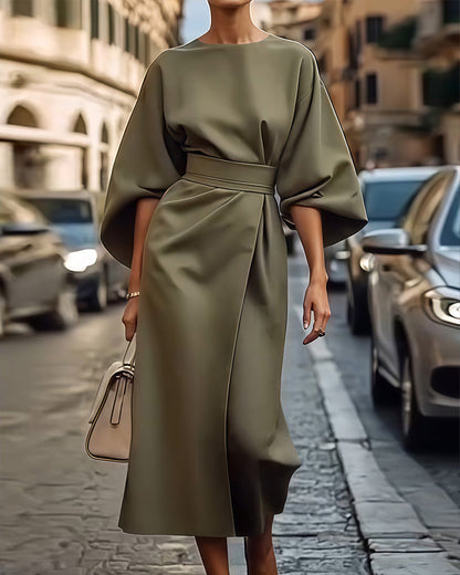 Olive green version of the belted dress with wide sleeves, worn with a cream handbag 2
