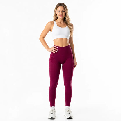 Front view of deep burgundy high-waisted leggings with subtle line detailing at the hips, worn with a white sports bra. 15