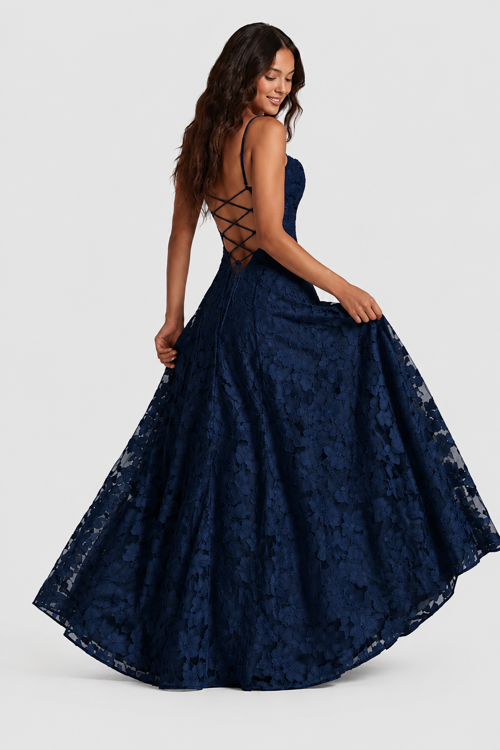 Navy lace gown from behind, model holding out the full skirt and showing the criss-cross lace-up back. 5