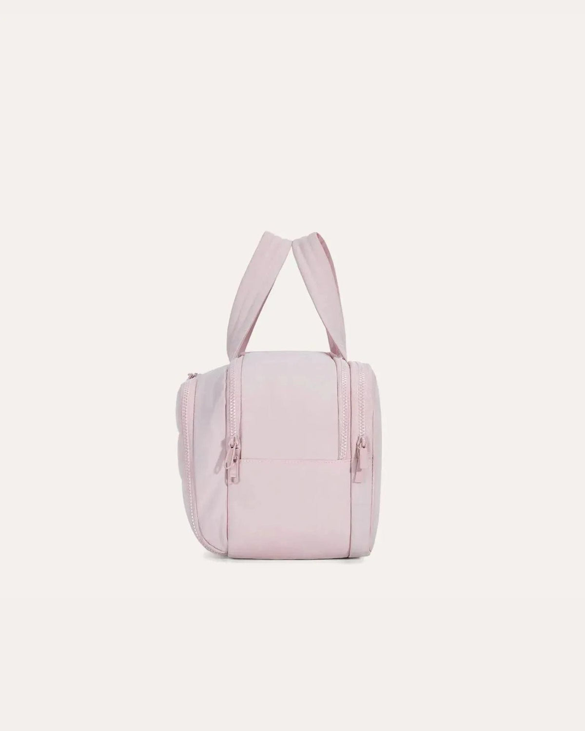 Side view of the pink bag standing upright, showing the zip pulls, a small pocket on the end panel and the padded handles. 10
