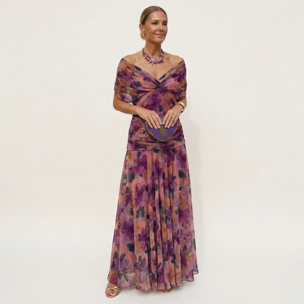 Full-length view of a purple and coral watercolour floral version with a twisted off-the-shoulder neckline and pleated skirt. 4