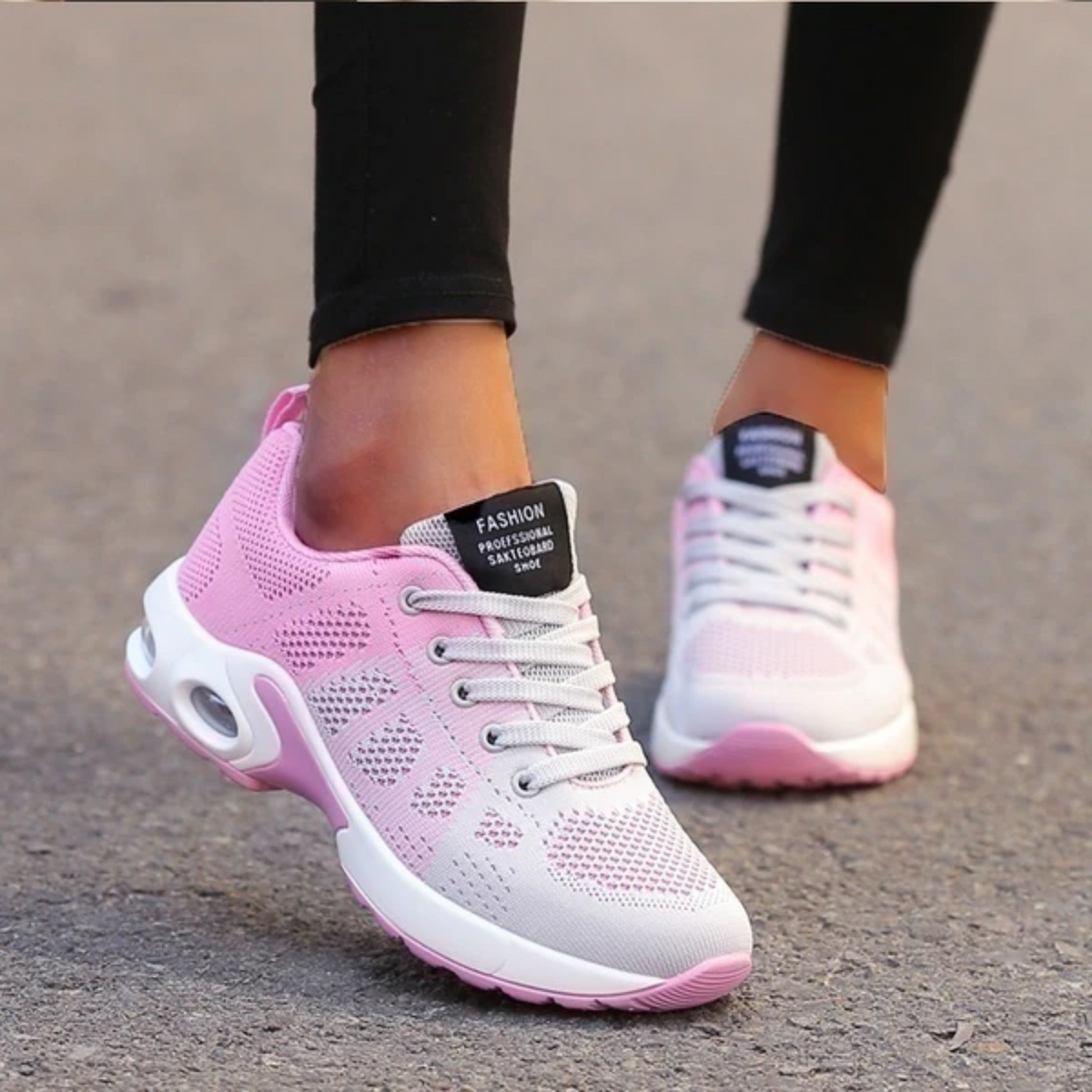 Pink and grey mesh trainers worn by a model in black leggings, mid-stride on a paved surface. 11