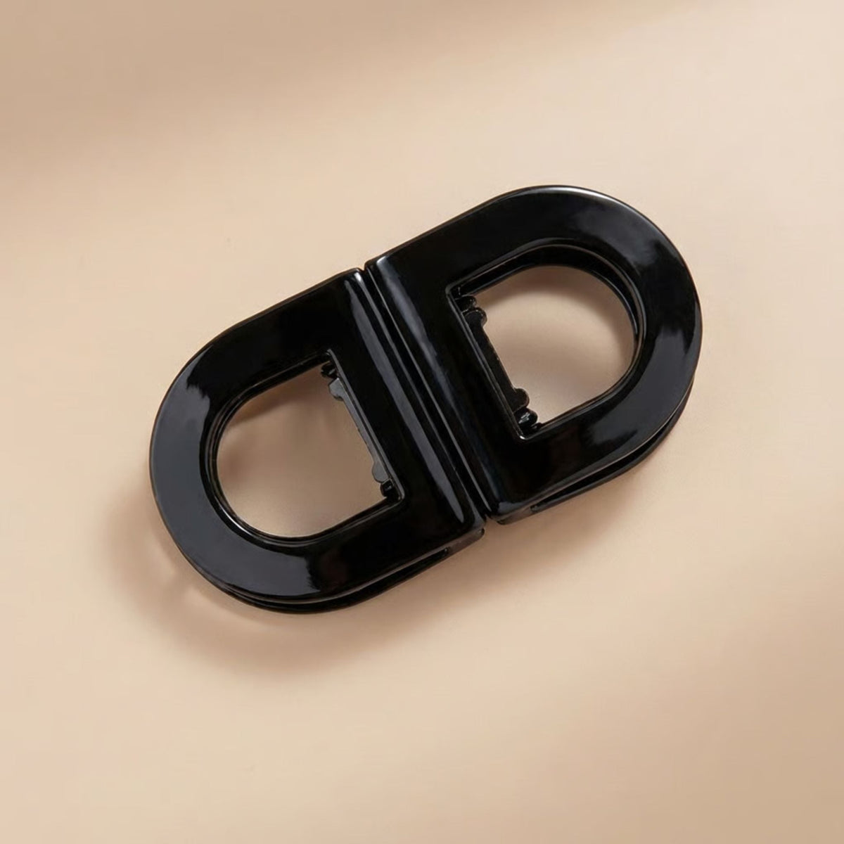 Glossy black oval flat hair clip with two open halves and a visible inner clasp, shown from above. 6