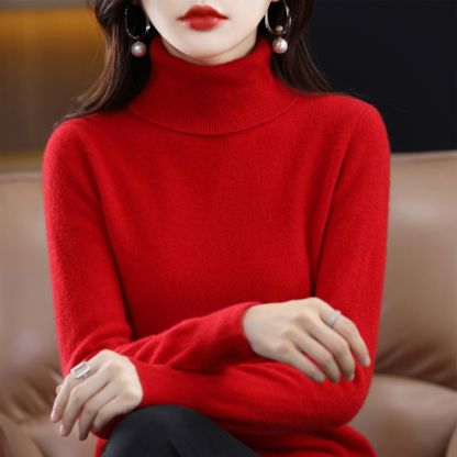 Model wearing the roll neck jumper in vivid red, arms crossed over her lap, seated on a tan sofa. 9