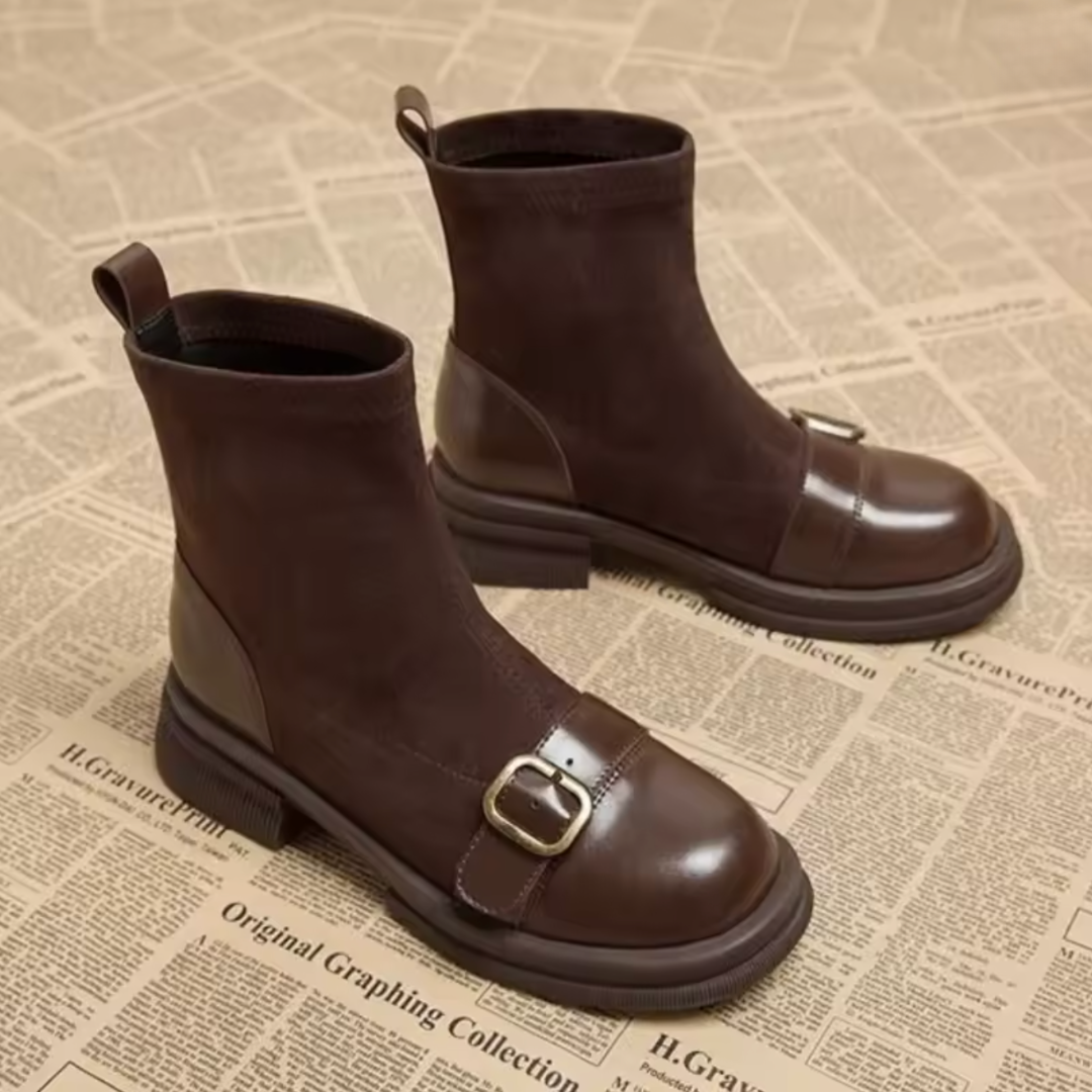 Brown suede ankle boots with polished leather toes and brass buckle straps, shown standing as a pair from a slightly raised front-side angle. 3