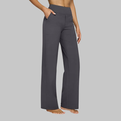 Side view of the high-waist straight-leg trousers in dark grey, worn by a barefoot model with a hand in the pocket. 6