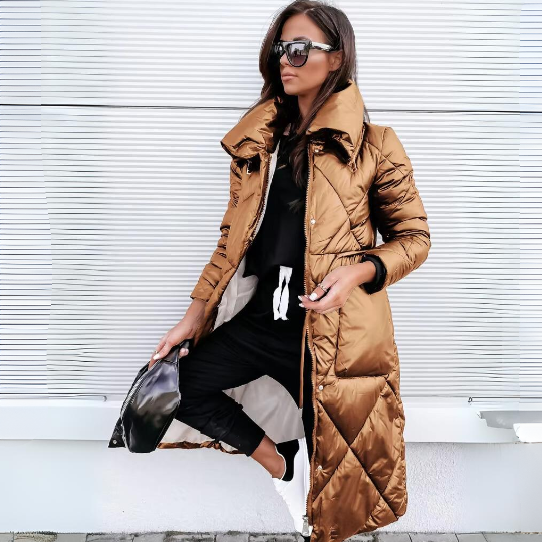 The same long quilted coat in a glossy bronze-brown shade, worn open by a model with black trousers and white trainers. 2