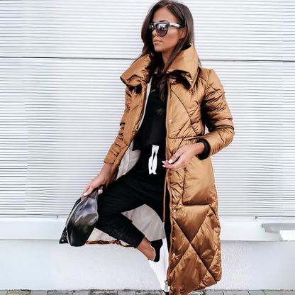 The same long quilted coat in a glossy bronze-brown shade, worn open by a model with black trousers and white trainers. 2
