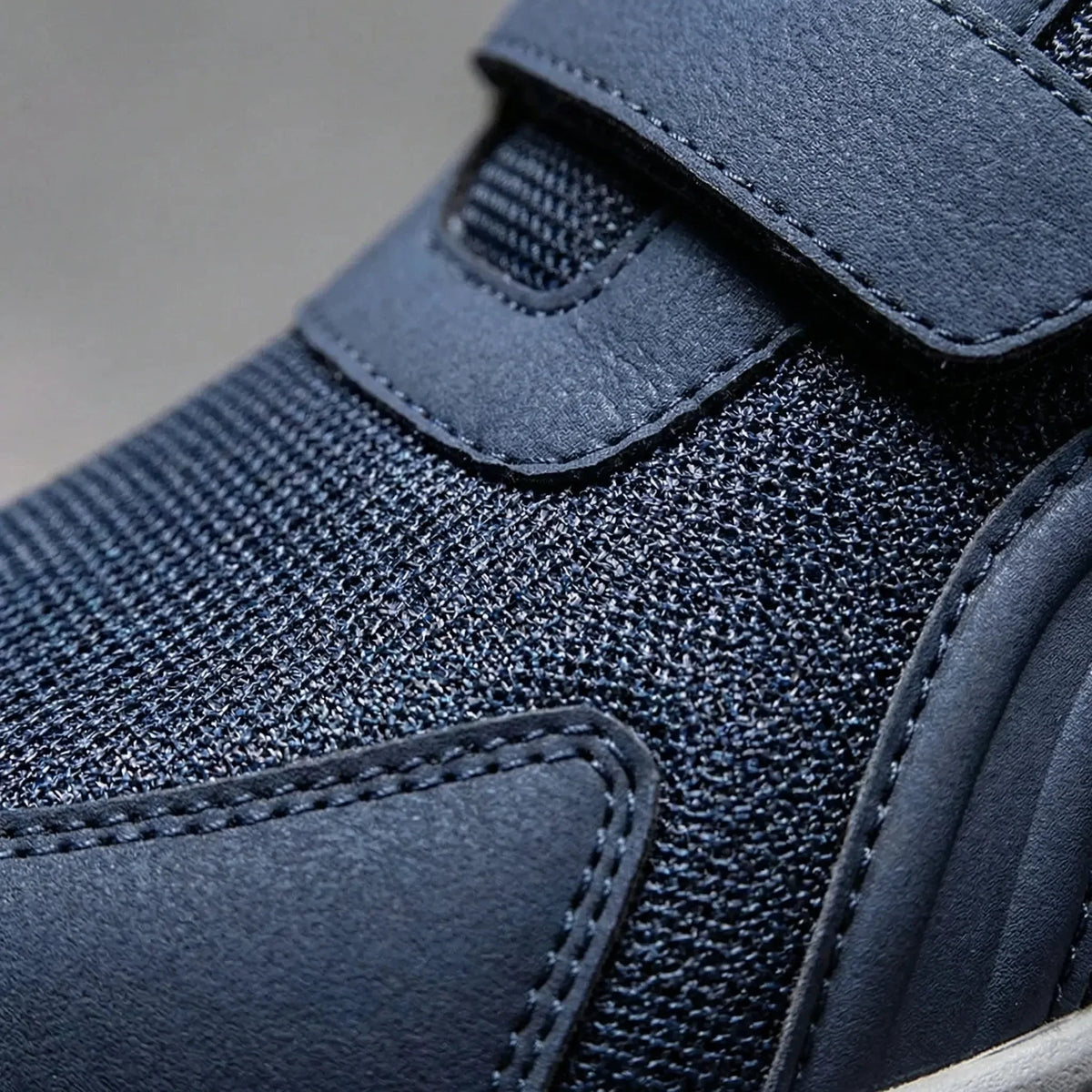 Extreme close-up of navy mesh upper, stitched overlay and strap on the shoe 10