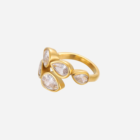 Gold-toned open-band ring with five clear pear-shaped crystals in smooth bezel settings, shown from a three-quarter side angle on a plain light background. 1