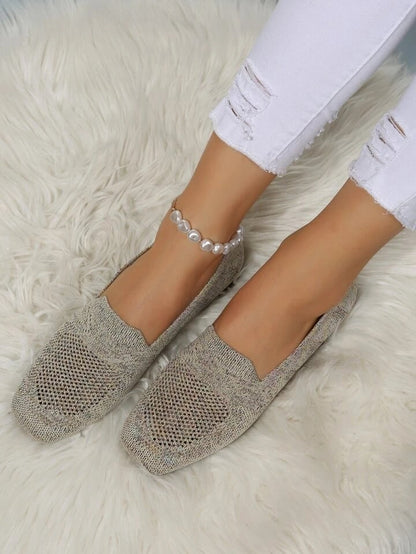 Taupe perforated knit slip-ons with square toes, worn on a fluffy white rug with white distressed jeans and a pearl anklet. 20