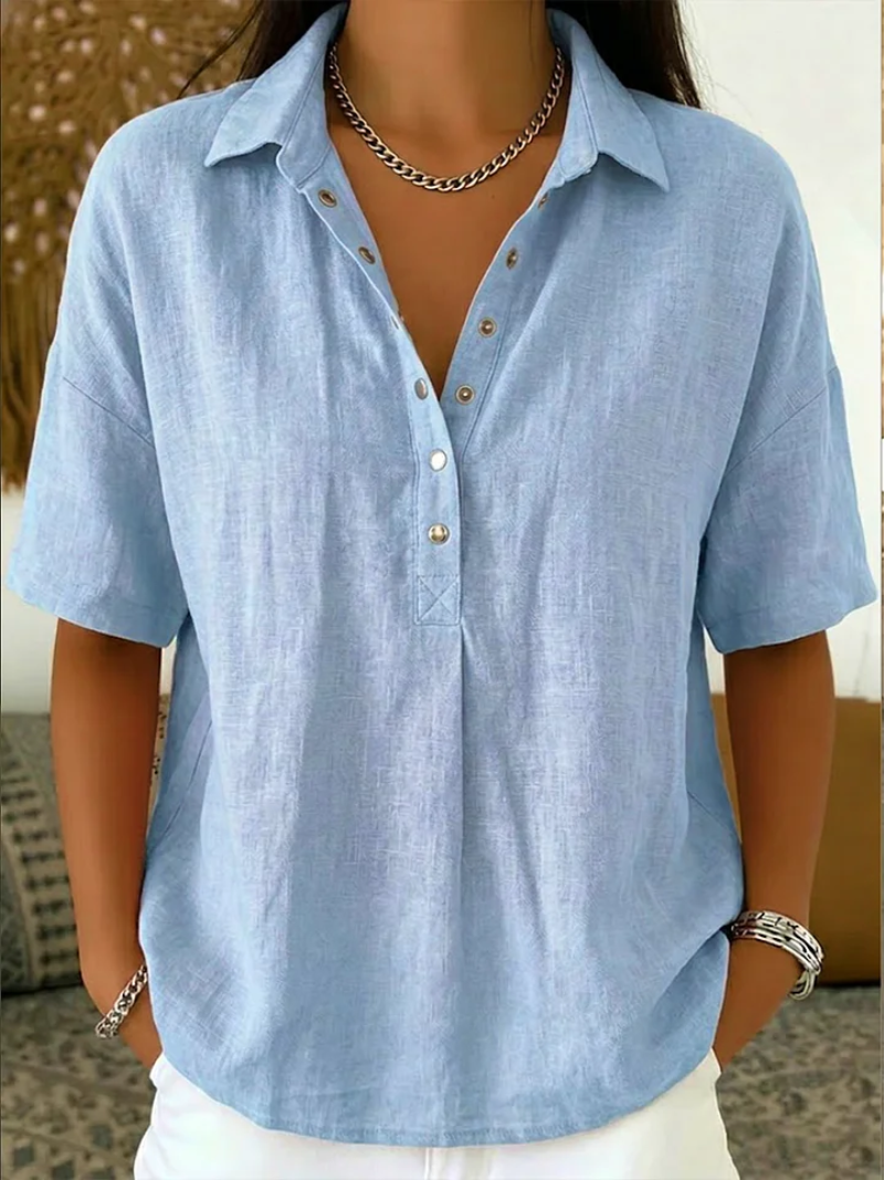 Short-sleeved blouse in pale sky blue, worn by a model with a chain necklace and white trousers 3
