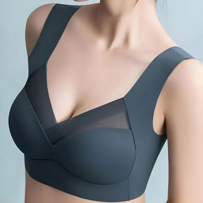 Close-up of a model wearing the slate-blue bra from the front, showing the V-neck mesh panel and wide straps. 2