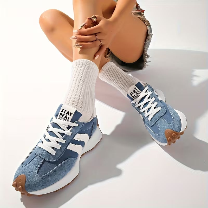 Model sitting with legs crossed, wearing blue suede trainers with white ribbed socks and denim shorts 9