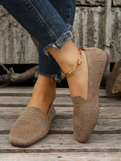 Brown mesh slip-ons worn with one foot crossed over the other, showing the back and side profile on a wooden floor. 6