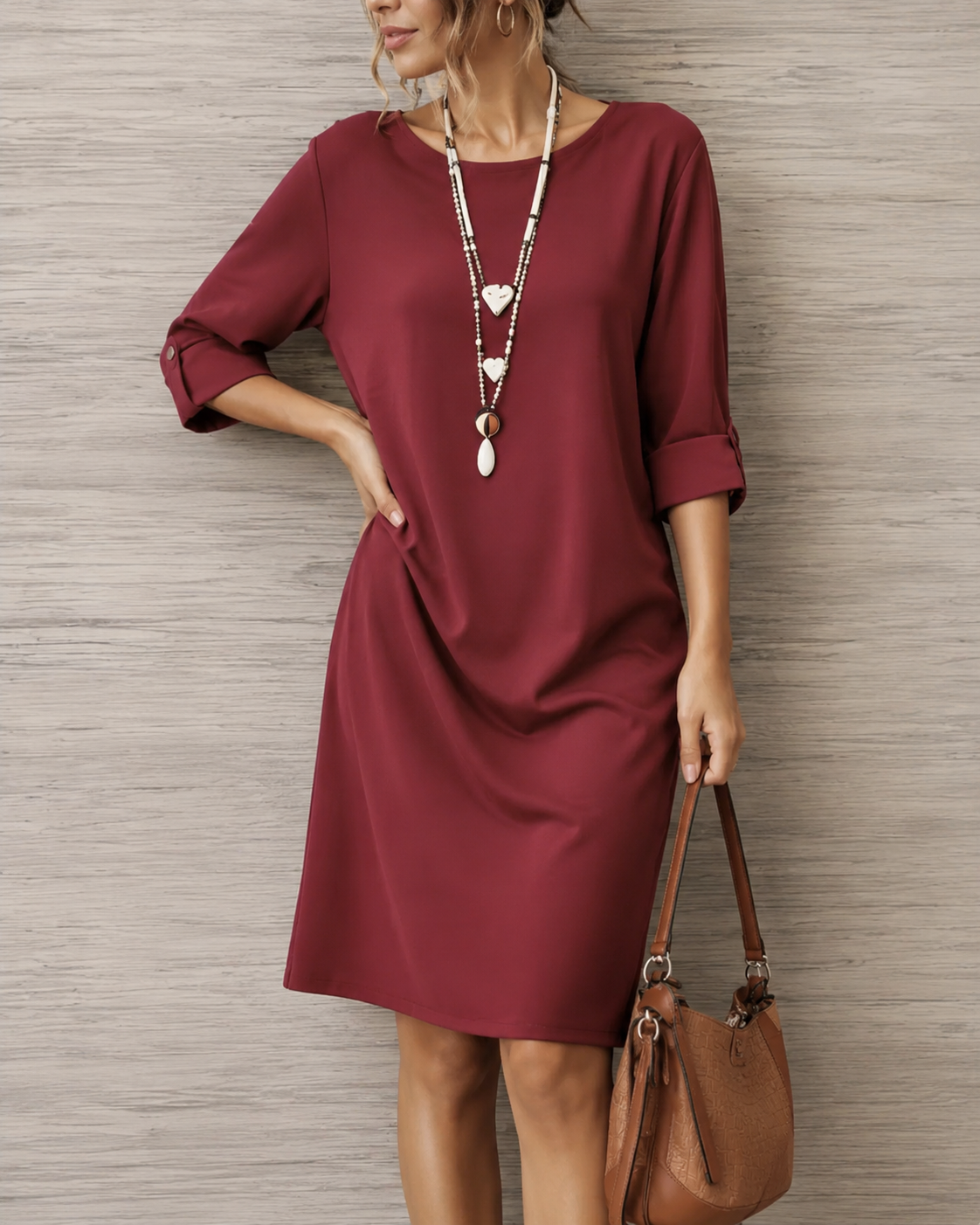Model wearing the burgundy dress with rolled sleeves, hand on hip, carrying a brown shoulder bag 6
