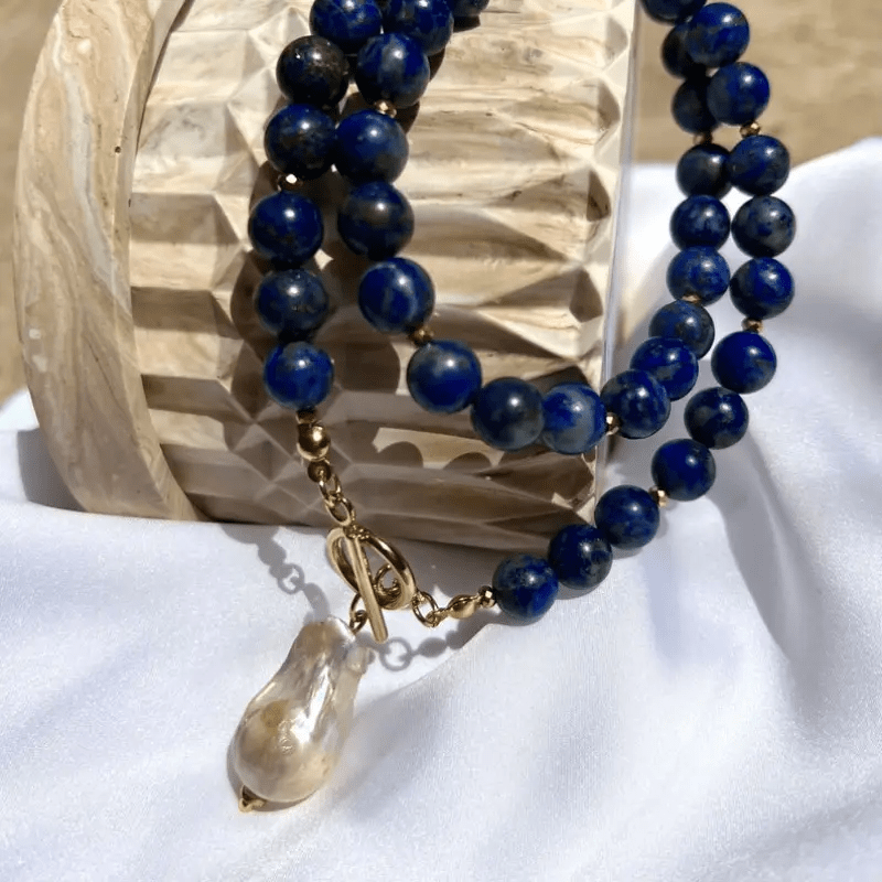 Necklace draped in two strands over a carved wooden holder, with the pearl hanging down 7