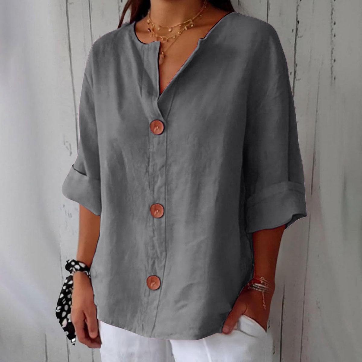 Model wearing the loose button-front blouse in mid grey, showing the notched V-neck, cuffed sleeves and three round brown buttons. 4