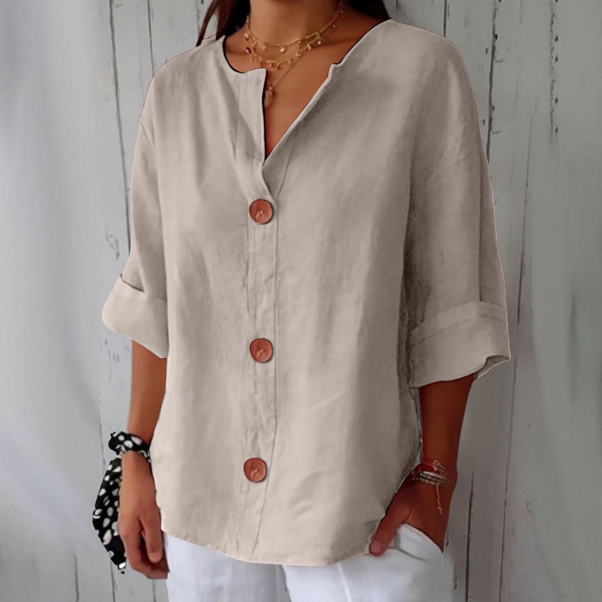 Model wearing the loose blouse in a soft beige shade with three large brown buttons, turned-back sleeves and layered gold necklaces. 3
