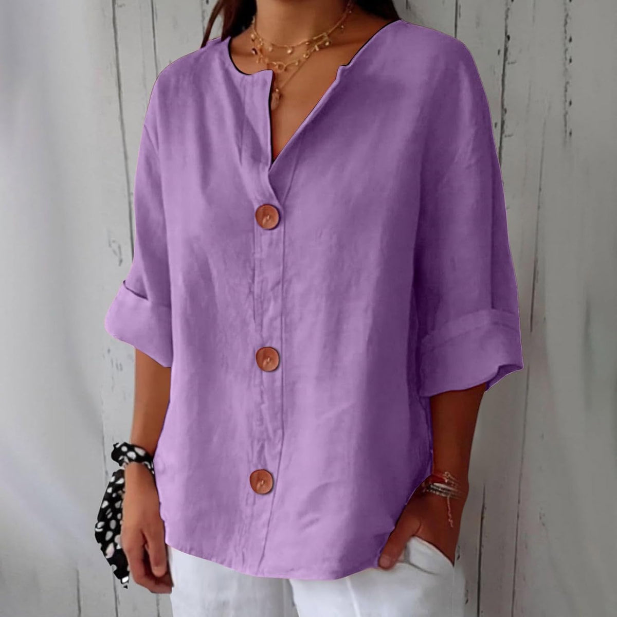 Model wearing the loose blouse in lilac purple with three round brown buttons, turned-up sleeves and a notched V-neckline. 10