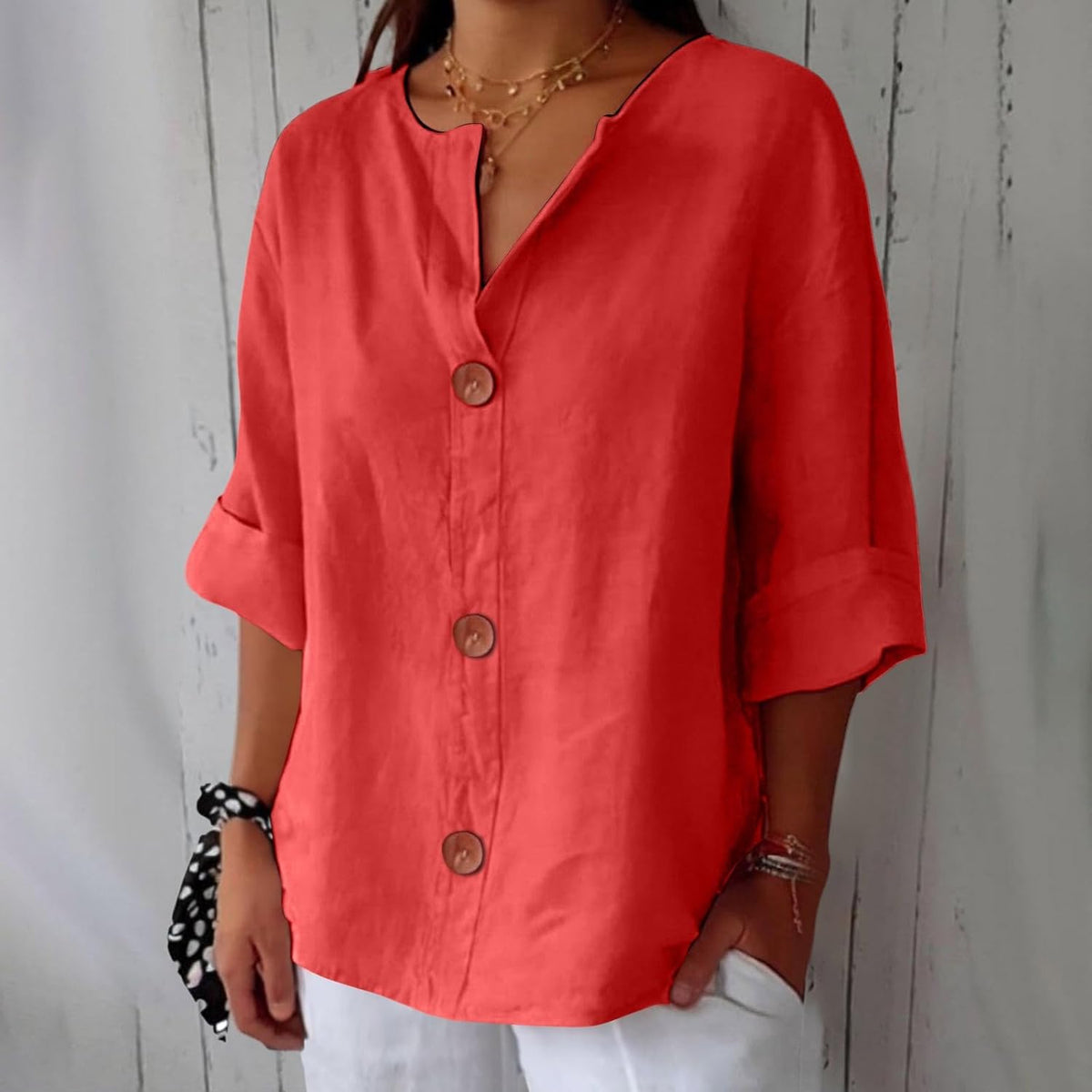 Model wearing the loose blouse in coral red with brown buttons down the front, rolled sleeves and white trousers. 5