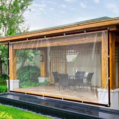 Clear tarpaulin hung as a weatherproof screen across the open side of a wooden garden pavilion, protecting the outdoor table and chairs. 3