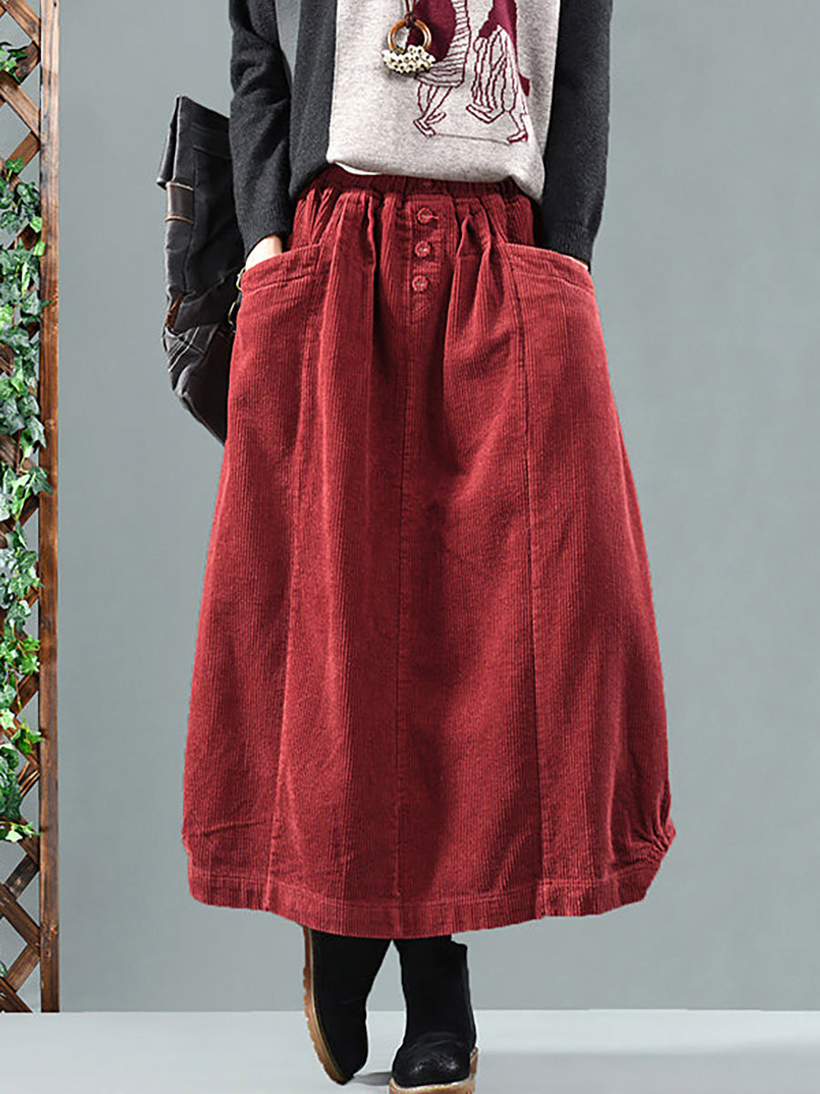 Model wearing the red corduroy skirt from the front with a grey jumper and black boots 1