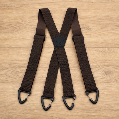 Dark brown X-back suspenders laid flat on a wooden surface, with a black stitched centre patch and four black triangular clips. 18