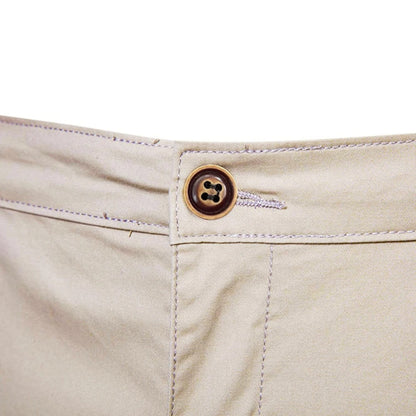 Close-up of the brown four-hole button and stitched waistband on the beige shorts 5