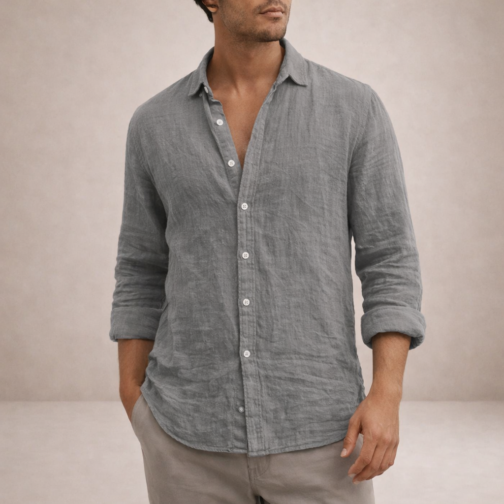 Torso view of a grey linen shirt with rolled sleeves and white buttons, worn with one hand in a stone trouser pocket. 2