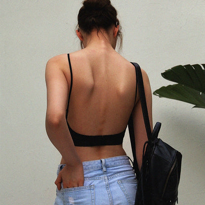 Back view of a model in the black bra, showing the open back, holding a rucksack 2