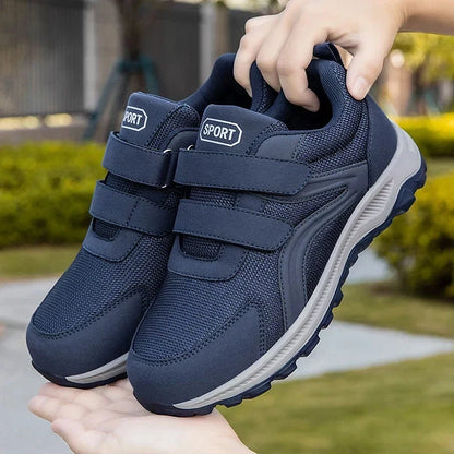 Hand holding a pair of navy strap shoes above an open palm in a garden 12