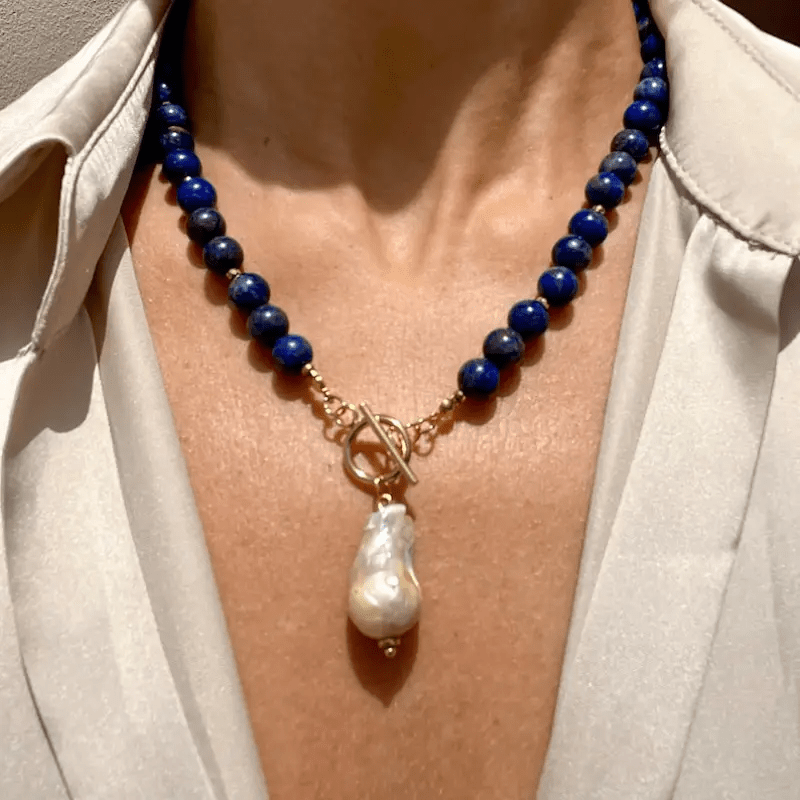 Necklace worn by a model over a cream blouse, with the baroque pearl hanging at the collarbone 1