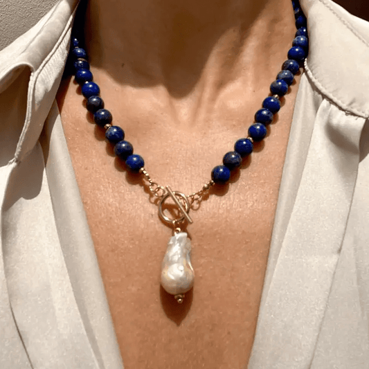 Necklace worn by a model over a cream blouse, with the baroque pearl hanging at the collarbone 1