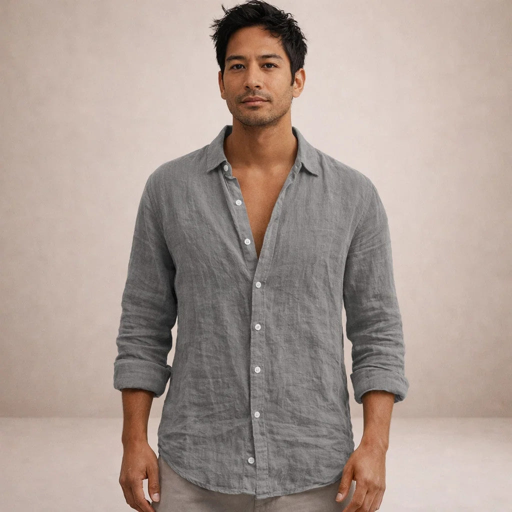 Full-face model wearing a grey crinkled linen shirt, collar open, sleeves rolled up, standing against a neutral backdrop. 8