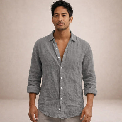 Full-face model wearing a grey crinkled linen shirt, collar open, sleeves rolled up, standing against a neutral backdrop. 8