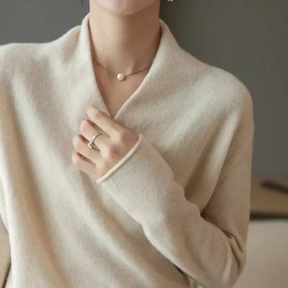 Close view of cream jumper's V-neckline and rolled cuff, with a hand touching the collar 5