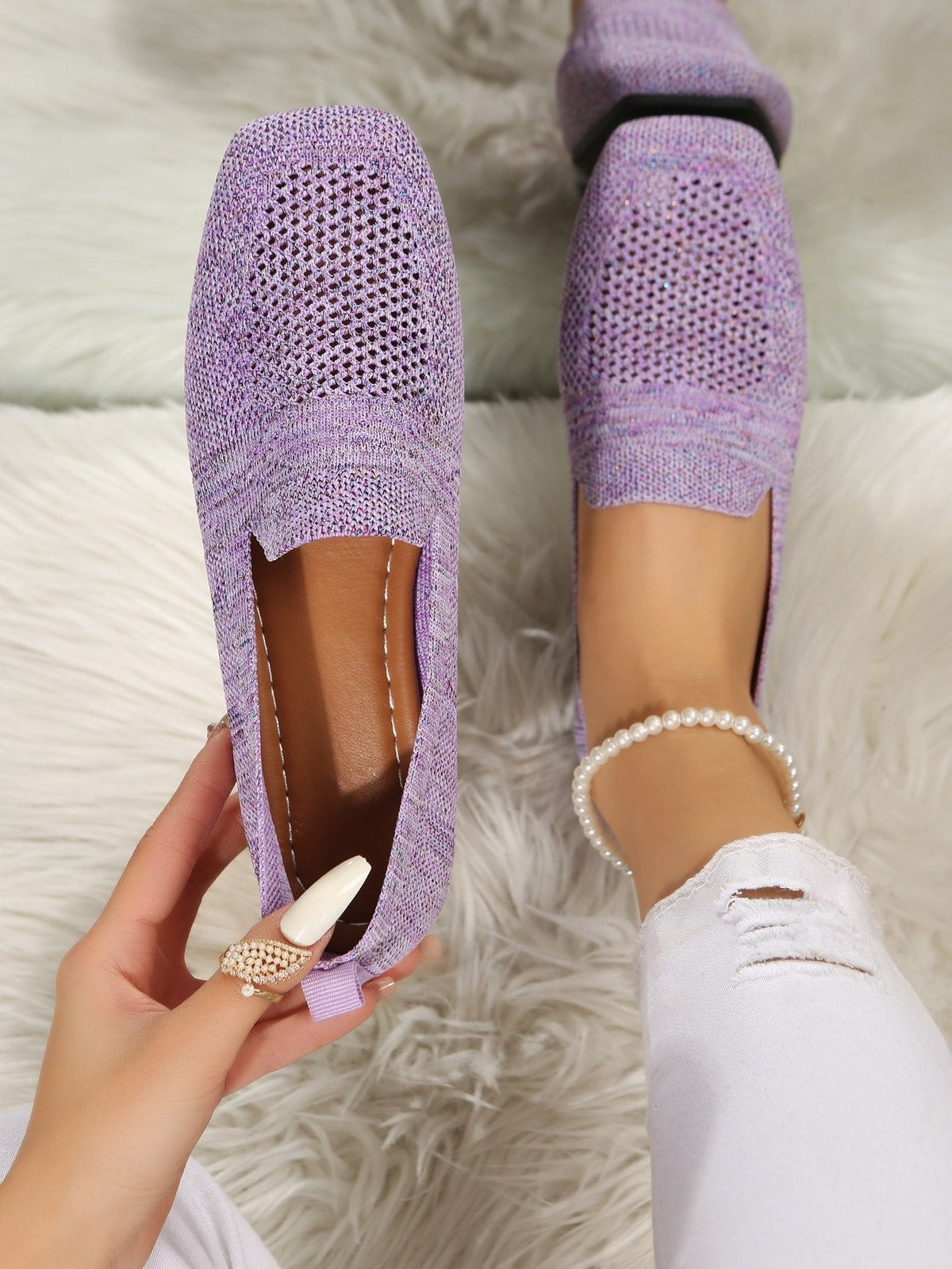 Top view of lilac mesh slip-ons on a fluffy rug, one held up to show the brown leather-look footbed. 11