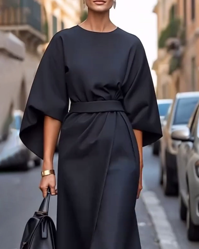 Close-up of the black dress's waist belt and wide sleeves, with a gold bracelet and black bag 5
