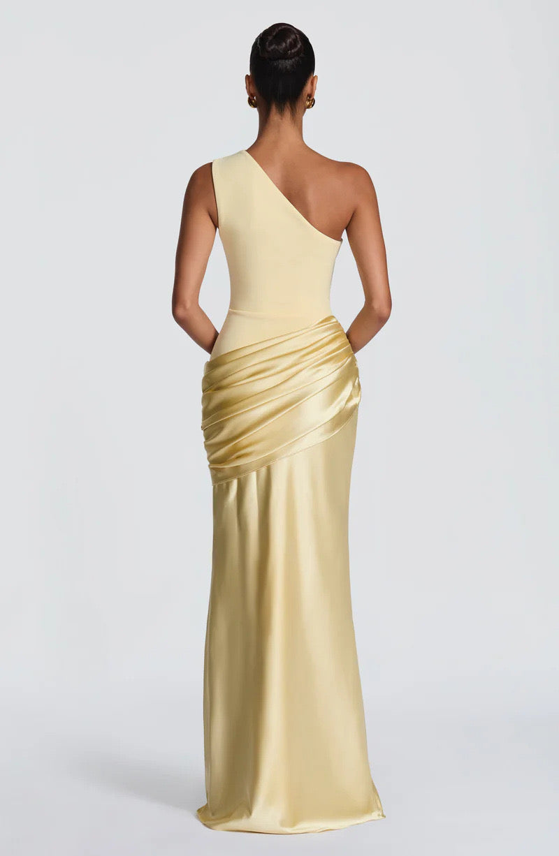 Back view of the pale yellow one-shoulder dress, showing the diagonal back neckline and draped satin panel across the hips. 27
