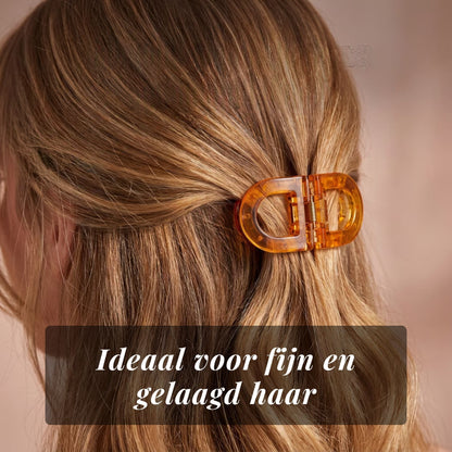 Close-up of the amber flat clip holding fine, layered blonde hair at the back of the head. 9