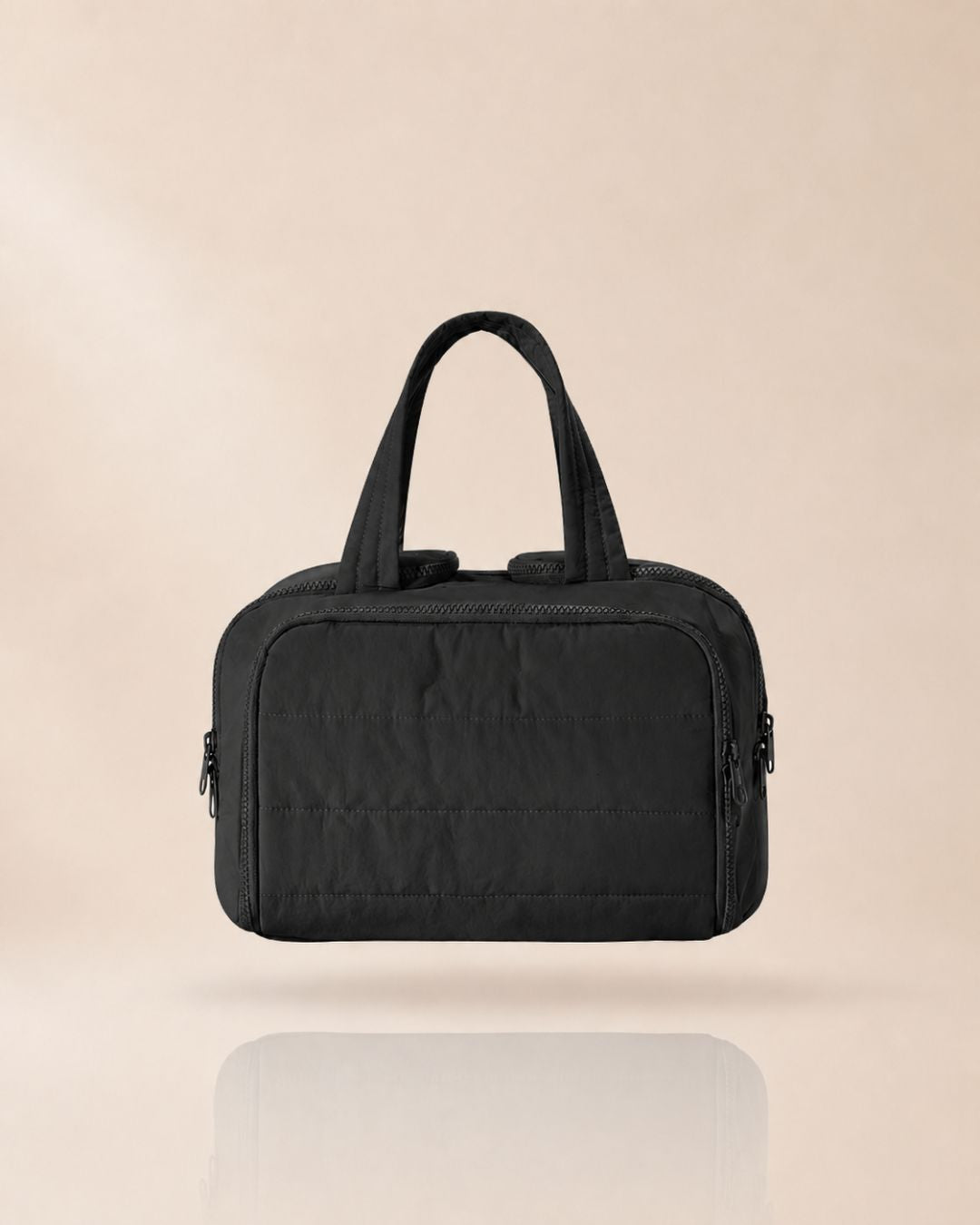 Black quilted organiser bag with two handles, front view on a soft beige background with a faint reflection. 12