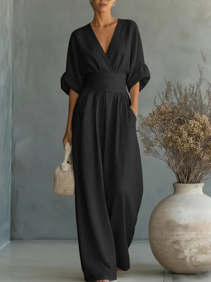 Same jumpsuit in black, front view of the wrapped V-neck bodice, pleated waistband and wide-leg trousers. 5