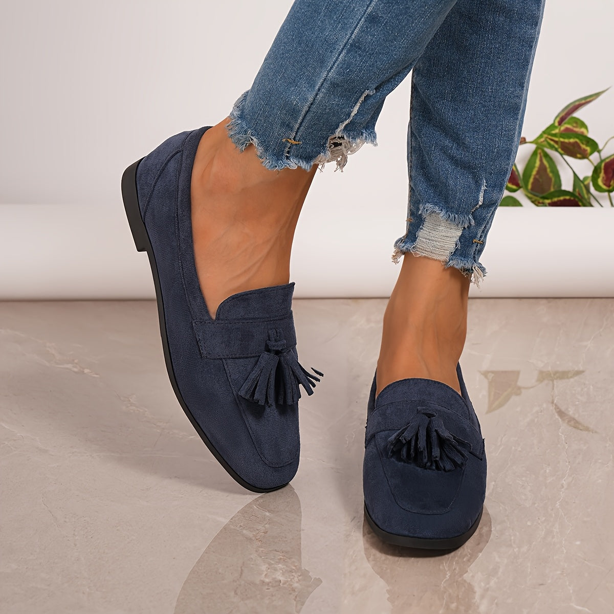 Navy tasselled loafers on a model's feet in frayed jeans, seen from the side 11