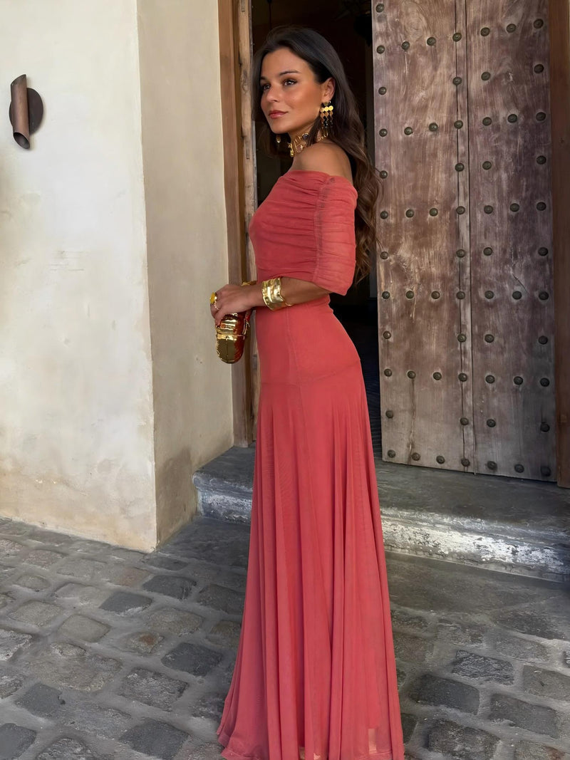 Terracotta dress worn off the shoulder with ruched short sleeves, seen from the side by a wooden door 6